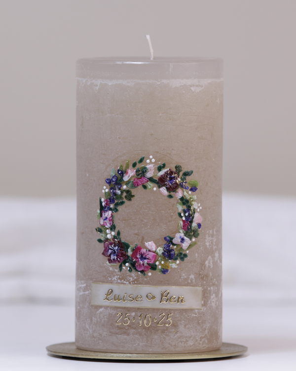 Sandgraue Hochzeitskerze mit farbenfrohem Blumenkranz – kunstvoll handverziert für den besonderen Tag.