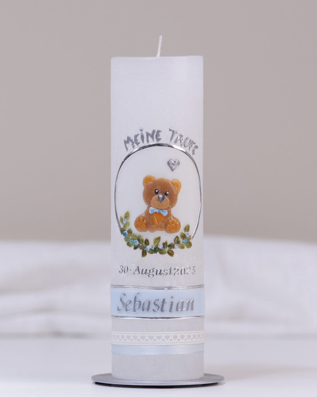Weiße Taufkerze mit silber-blauer Verzierung aus handgeformtem Bärchen, Kreuz, Herzchen und Blumenranke.
